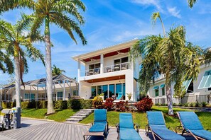 A two-story house with a balcony, a deck, and lounge chairs. - Dog-friendly waterfront getaway with lanai, private pool, & pool spa (Marco Island)