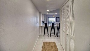 A hallway with a kitchen area, white walls, and a ceiling with recessed lighting. - Amazing oceanfront condo with pool, hot tub, tennis, & stunning balcony views (Marco Island)