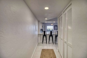 A hallway with a kitchen area, white walls, and a ceiling with recessed lighting. - Amazing oceanfront condo with pool, hot tub, tennis, & stunning balcony views (Marco Island)