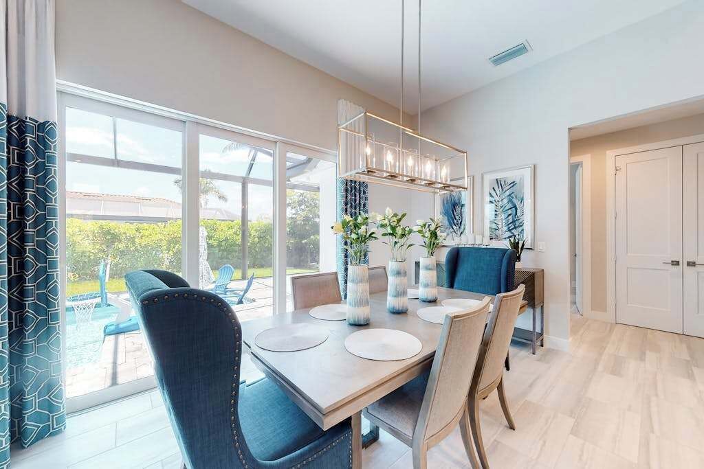 A modern dining area with a large table, chairs, and a hanging light fixture.