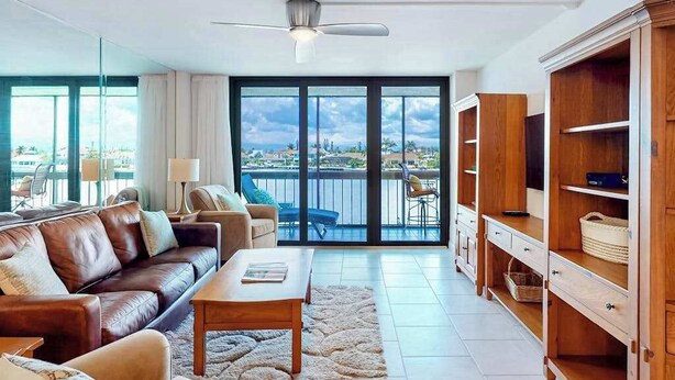 Een moderne woonkamer met een leren bank, een salontafel, een tv-meubel en een balkon met uitzicht.