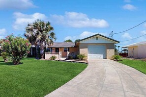 Einbungalow mit Garage, einem gepflegten Rasen und einer Palme.