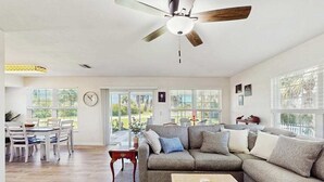 A spacious living room with a sectional sofa, dining table, and chairs, large windows, and a ceiling fan. - Waterfront home with, private grill, and washer and dryer, and Gulf access (Fort Myers Beach)