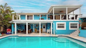 A two-story house with a swimming pool, a balcony, and a covered patio area. - Spacious home with heated pool, lots of outdoor entertainment, and WIFI (Fort Myers Beach)