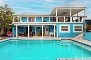 A two-story house with a swimming pool, a balcony, and a covered patio area.