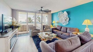 A living room with a sofa, armchairs, a coffee table, and a TV. - Beachfront condo with huge lanai, sunset gulf views, pool, hot tub, tennis & gym (Marco Island)