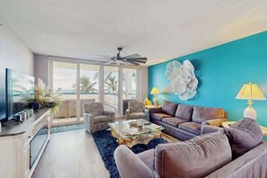 Ein Wohnzimmer mit einer Couch, Sesseln, einem Couchtisch und einem Fernseher.