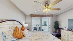 A bedroom with a bed, a ceiling fan, a view of the outdoors, a desk, and a chair. - Beachfront condo with huge lanai, sunset gulf views, pool, hot tub, tennis & gym (Marco Island)