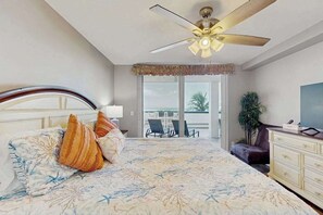 Ein Schlafzimmer mit Bett, Deckenventilator, Blick ins Freie, Schreibtisch und Stuhl.