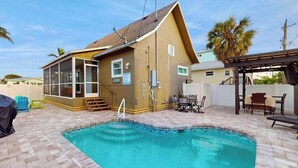A pool area with a wooden house, outdoor furniture, and a covered seating area. - Bright & breezy beach house with private pool, sunroom, washer/dryer, & AC (Fort Myers Beach)