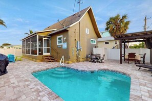 A pool area with a wooden house, outdoor furniture, and a covered seating area. - Bright & breezy beach house with private pool, sunroom, washer/dryer, & AC (Fort Myers Beach)