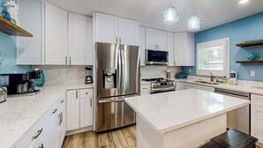 A modern kitchen with white cabinetry, stainless steel appliances, and a central island. - Bright & breezy beach house with private pool, sunroom, washer/dryer, & AC (Fort Myers Beach)