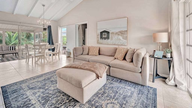 A spacious living room with a large sectional sofa, a coffee table, and a dining area with chairs. - Updated tropical home with a private patio, beach gear, AC, and washer/dryer (Marco Island)