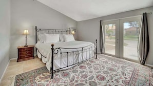 A bedroom with a bed, nightstand, lamp, and a view through a glass door. - Updated tropical home with a private patio, beach gear, AC, and washer/dryer (Marco Island)