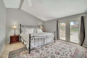 A bedroom with a bed, nightstand, lamp, and a view through a glass door. - Updated tropical home with a private patio, beach gear, AC, and washer/dryer (Marco Island)
