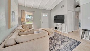 A living room with a sofa, TV, and a fireplace. - Updated tropical home with a private patio, beach gear, AC, and washer/dryer (Marco Island)