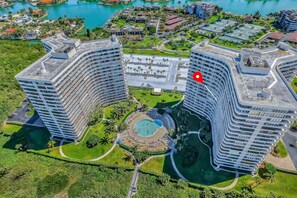 Ein Hochhaus-Hotel mit einem zentralen Schwimmbecken, umgeben von üppiger Bepflanzung und einer Marina.