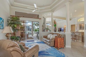 A spacious living area with a leather sofa, a coffee table, and a large window. - Waterfront home with saltwater pool, pool spa, central AC, W/D, & office space (Marco Island)