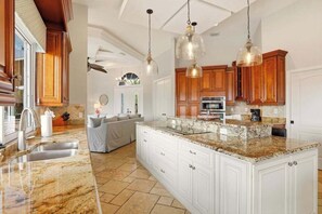 A kitchen with granite countertops, wooden cabinets, and pendant lighting. - Large corner lot home with canal views & screened in pool - close to the beach (Marco Island)
