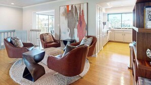 A living room with brown leather chairs, a round coffee table, and a large abstract painting on the wall.