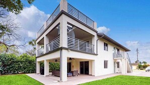 A modern two-story house with a covered patio, a balcony, and a garage. - Dog-friendly colorful condo with shaded patio, washer/dryer, & central AC (Naples)