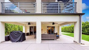 A two-story building with a covered patio area, outdoor seating, and a balcony. - Dog-friendly colorful condo with shaded patio, washer/dryer, & central AC (Naples)