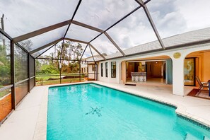 A swimming pool with a covered area, a patio with outdoor furniture, and a view of the surrounding landscape. - Dog-Friendly Pool Retreat with Lanai, Grill & Central Location (Port Charlotte)