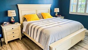 Een slaapkamer met een bed, twee nachtkastjes en een raam.