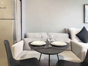 Un espace de vie moderne comprenant un canapé, une petite table et un réfrigérateur.