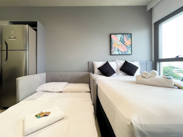 Une chambre d’hôtel avec un lit, un canapé, un réfrigérateur et une fenêtre donnant sur un beau paysage.