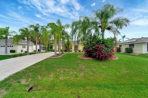 A residential area with houses, a well-maintained lawn, and palm trees. - Relax & Recharge in This Spacious Port Charlotte Retreat with Pool & More! (Port Charlotte)