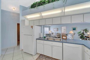 A modern kitchen with white cabinets, a built-in refrigerator, a sink, and a countertop with a blue backsplash. - Relax & Recharge in This Spacious Port Charlotte Retreat with Pool & More! (Port Charlotte)