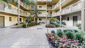 Un edificio de varios pisos con balcones, un patio central con plantas y un cielo despejado.