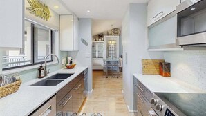 Una cocina moderna con una isla central, electrodomésticos de acero inoxidable y vistas al área de comedor.