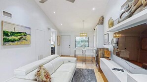 Una sala de estar moderna con un sofá blanco, un comedor y una cocina al fondo.