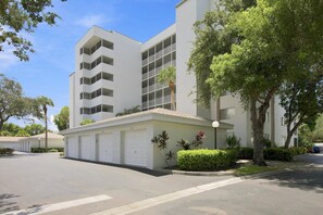 A modern multi-story building with a flat roof, large windows, and a garage entrance. - 3rd-floor snowbird-friendly condo with enclosed balcony, outdoor pool, W/D, AC (Naples)