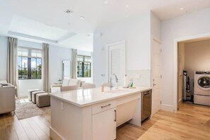A modern kitchen with a central island, built-in appliances, and a large window. - Contemporary dog-friendly studio with central AC and washer/dryer (Naples)