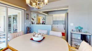 A modern kitchen with white cabinets, a stainless steel refrigerator, and a dining area with a round table and chairs. - Close to Gulf with pool & updated interior (Rotonda West)