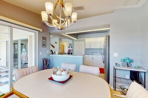 A modern kitchen with white cabinets, a stainless steel refrigerator, and a dining area with a round table and chairs. - Close to Gulf with pool & updated interior (Rotonda West)