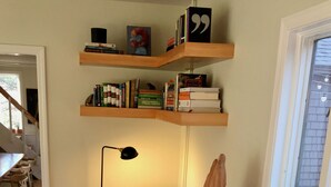 Un salon chaleureux avec un canapé, un meuble en bois, une bibliothèque, une lampe sur pied et une fenêtre donnant sur un beau paysage.