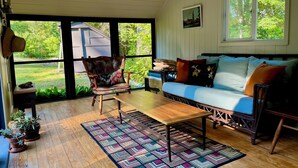 Une pièce chaleureuse avec un plancher en bois, un tapis à motifs, un canapé avec des coussins, un fauteuil et une table.