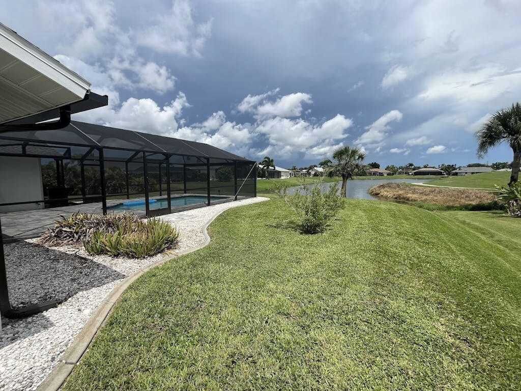 A modern building with a covered outdoor area, a well-maintained lawn, and a small pond.