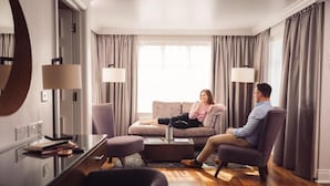 A modern living room with a sofa, armchairs, a coffee table, and a glass desk with a lamp. - Ivanhoe Hotel (Belfast)