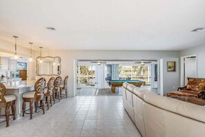 A spacious living area with a pool table, a sofa, and a dining area with chairs and a bar.