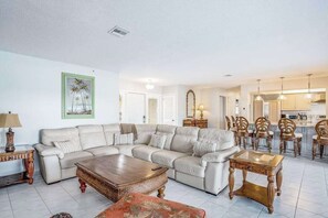 A living room with a sectional sofa, a coffee table, and a dining area with chairs.