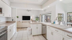 Een moderne keuken met witte kasten, een vaatwasser en een eethoek met een tafel en stoelen.