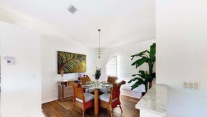 A dining area with a round table, wicker chairs, a chandelier, and a large plant. - Bohemian canal-front retreat with pool, beach gear, adult bikes, & AC - dogs ok (Rotonda West)