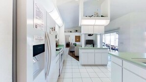 A modern kitchen with white cabinetry, a built-in island, and a dining area with a view. - Bohemian canal-front retreat with pool, beach gear, adult bikes, & AC - dogs ok (Rotonda West)