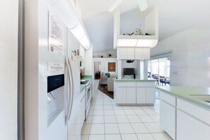 A modern kitchen with white cabinetry, a built-in island, and a dining area with a view. - Bohemian canal-front retreat with pool, beach gear, adult bikes, & AC - dogs ok (Rotonda West)