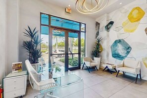 A modern reception area with glass furniture, a large window, and a wall with abstract art. - Exceptional condo with balcony, WIFi, and located close to beaches and downtown (Naples)